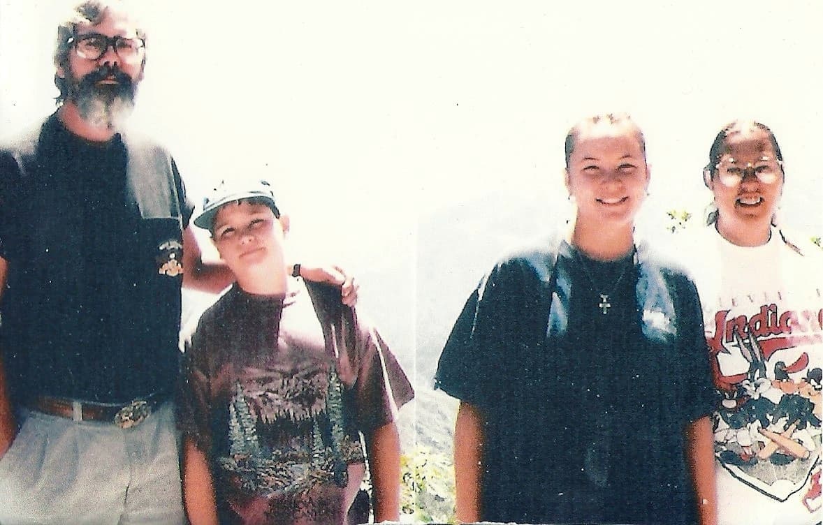 A color 90s photograph of Russell at 10 years old with his father and his sister standing with his mother at the zoo